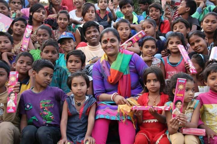 Parvarish children gathered around a teacher on a festival day, holding boxes of sparklers.